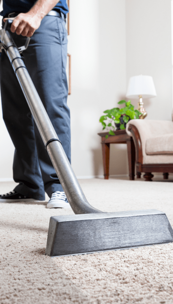 A person using a vacuum on the floor of their living room.