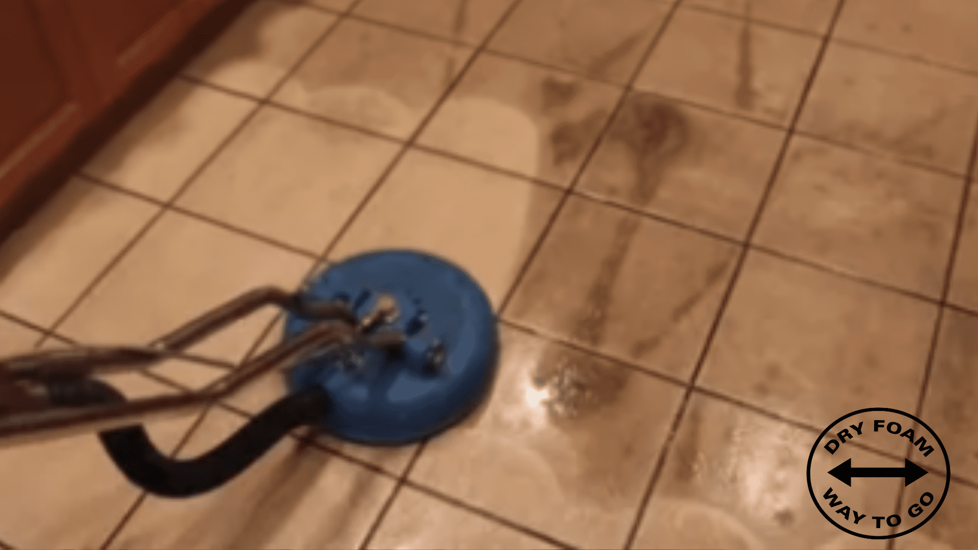 A blue mop is on the floor of a tiled room.