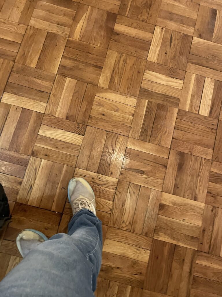 A person's feet on a parquet floor.